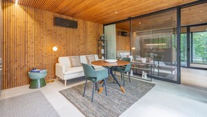 Ein modernes Interieur mit Holzboden, einem weißen Sofa, Türkis-Stühlen und einer Glastrennwand.