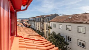 A view from a balcony with terracotta roof tiles, overlooking a row of buildings with varied architectural styles and a clear sky. - Living Valverde Studio Azul - Minho s Guest (Braga)