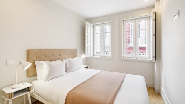 A bedroom with a bed, nightstands, a lamp, and two windows. - Porta 120 S o Vicente by Minho s Guest (Braga)