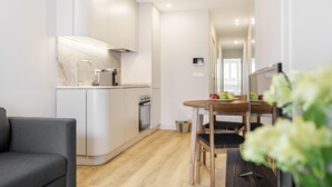 A modern kitchen with white cabinets, a marble countertop, and a wooden dining table with chairs. - Porta 120 S o Vicente by Minho s Guest (Braga)