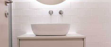 Un baño con un lavamanos blanco, un espejo redondo y un suelo con diseño.