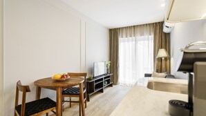 A modern hotel room with a wooden dining table, chairs, a TV, a sofa, a lamp, and a minibar. - Porta 120 S o Vicente by Minho s Guest (Braga)