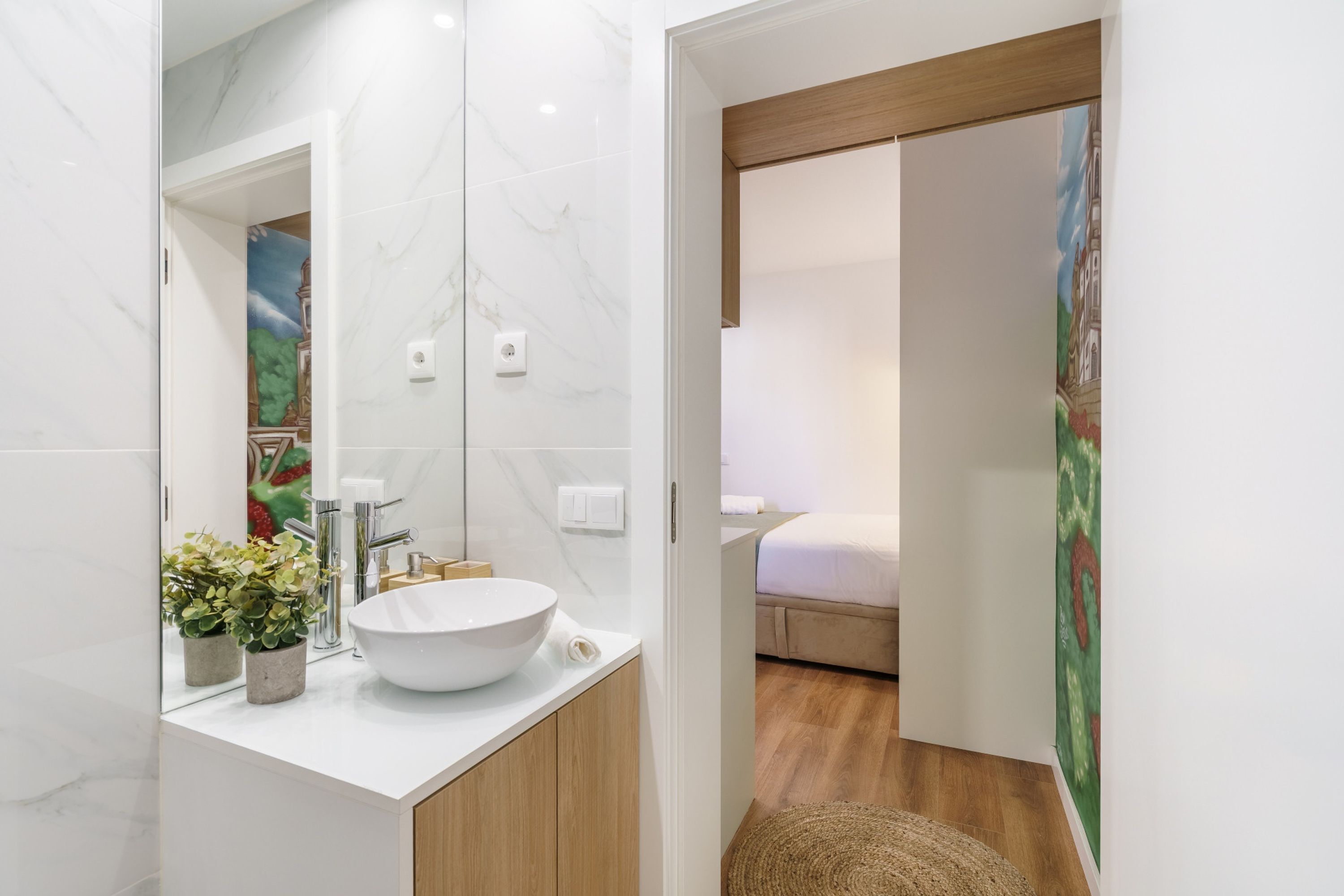 Ein modernes Badezimmer mit einem weißen Waschbecken, einer Marmor-Spritzschutzleiste und Holzelementen.