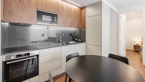 A modern kitchen with wooden cabinets, stainless steel appliances, and a dark countertop. - 196 Andrade Corvo Apartment by Minho s Guest (Braga)