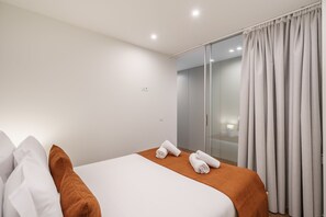 A hotel room with a bed, white and brown pillows, a brown blanket, and two rolled towels. - 196 Andrade Corvo Apartment by Minho s Guest (Braga)