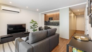 A modern living room with a grey sofa, a flat-screen TV, and a dining area with a table and chairs. - 196 Andrade Corvo Apartment by Minho s Guest (Braga)
