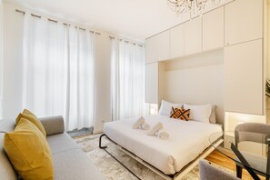 Une chambre d’hôtel moderne avec un grand lit, un canapé, une table en verre et une chaise.
