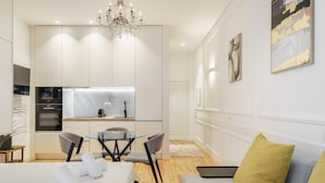 A modern hotel room with a dining area, kitchenette, and a sofa with a yellow pillow. - Ch os Concept By Minhos Guest (Braga)