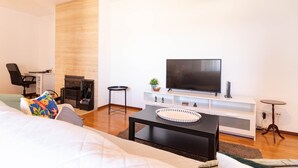 A modern living room with a flat-screen TV, a sofa, a coffee table, a fireplace, and a small side table. - Machado s Lodge - Minho s Guest (Braga)