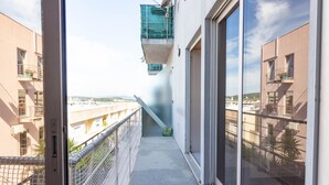 A narrow balcony with a metal railing, a concrete floor, and a view of adjacent buildings. - Machado s Lodge - Minho s Guest (Braga)