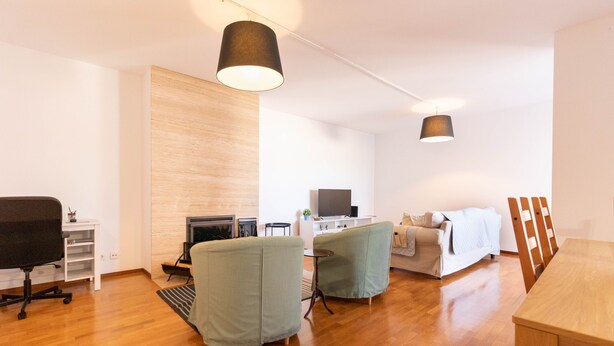 A modern living room with a wooden floor, a sofa, two armchairs, a dining table, and a TV. - Machado s Lodge - Minho s Guest (Braga)