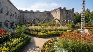 A historic building with a fortified structure, surrounded by a well-maintained garden with various flower beds and a paved pathway. - Santa Barbara Flat by Minhos Guest (Braga)