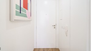 A hallway with a white door, a framed abstract painting, and a wooden floor. - Santa Barbara Flat by Minhos Guest (Braga)
