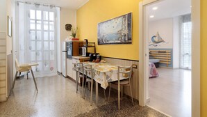 Uma área de refeições com uma mesa posta para quatro pessoas, uma cadeira, um micro-ondas e um quadro na parede.
