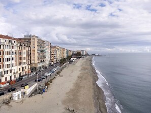 Un paysage urbain côtier avec des immeubles à plusieurs étages, une plage et une mer calme.