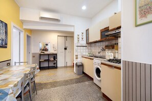 Une cuisine compacte comprenant un lave-linge, une table à manger avec des chaises et un petit coin repas.