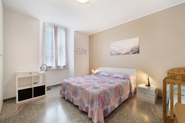Un dormitorio con cama, mesita de noche y cuna.