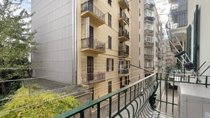 Um edifício residencial com vários andares, varandas, guarda-corpo verde e vista para a rua.