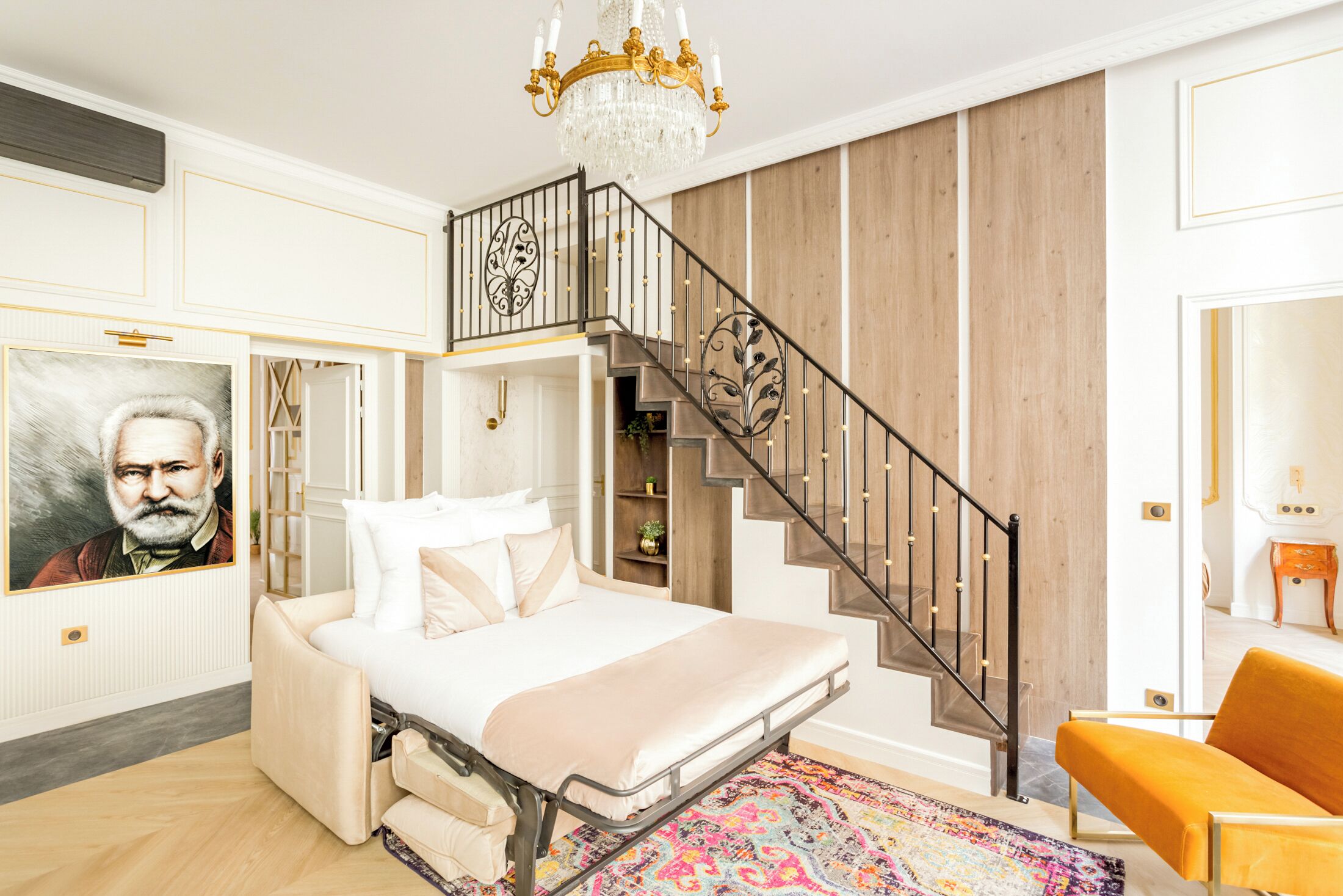 Ein Schlafzimmer mit einem Bett, einer Treppe, einer Chandelüster und einem Gemälde an der Wand.