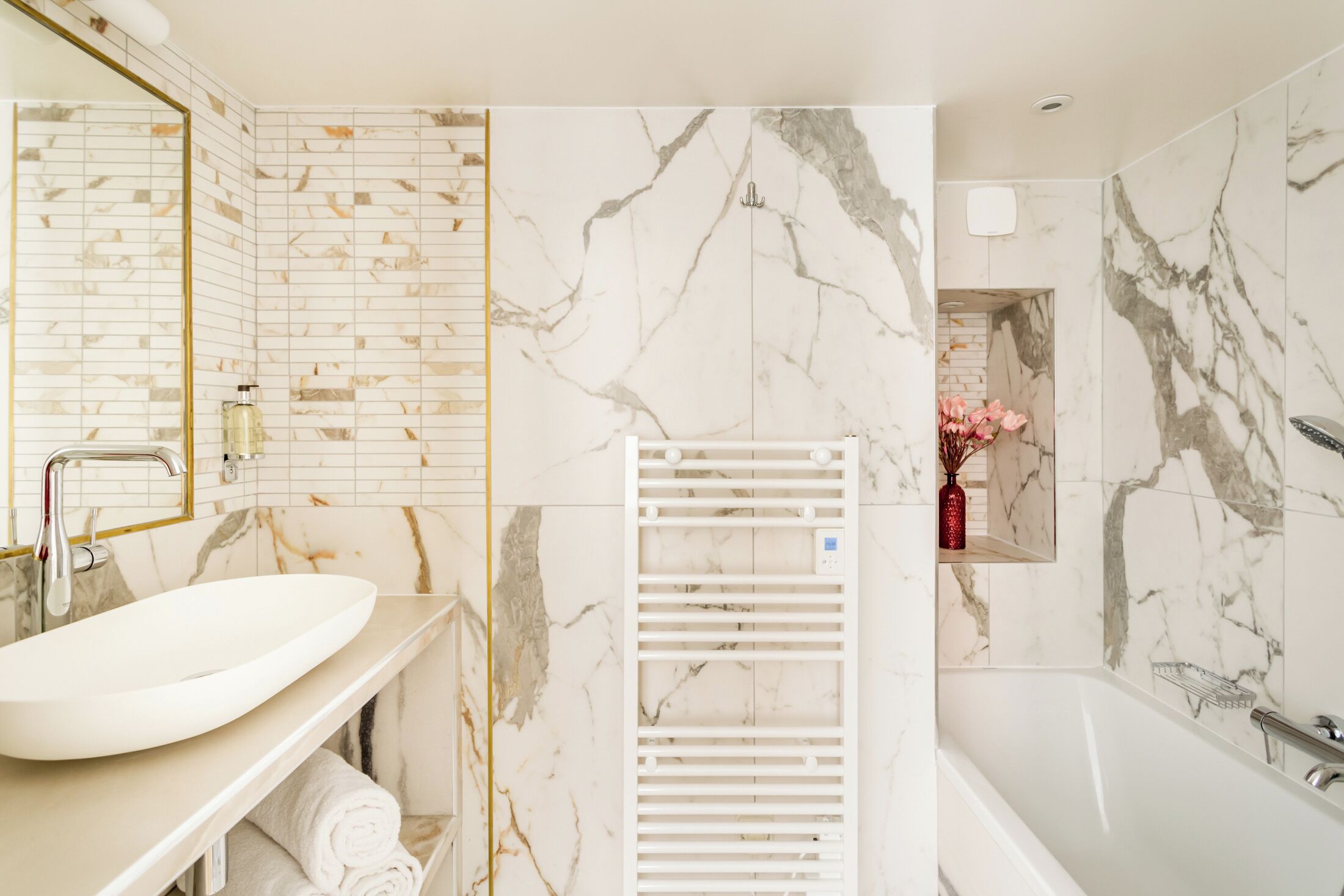 A bathroom with a white sink, a mirror, a towel rack, and a bathtub.