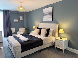 A modern bedroom with a large bed, bedside lamps, a headboard, a bedside table, and a wall-mounted artwork. - Toast Stays - The Oakley at Parsons House (Washington)
