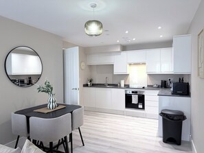 A modern kitchen with white cabinets, a black countertop, and a round mirror. - Toast Stays - The Oakley at Parsons House (Washington)