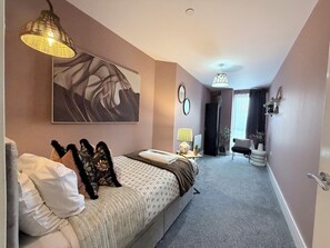 A bedroom with a bed, bedside table, lamp, and a large abstract painting. - Toast Stays - The Oakley at Parsons House (Washington)