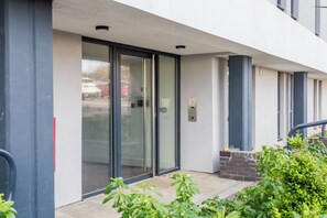 A building entrance with a glass door, a keypad entry system, and a small brick structure to the right. - Toast Stays - The Oakley at Parsons House (Washington)
