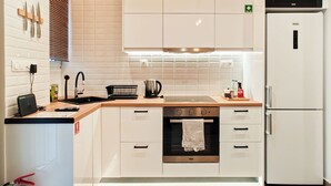A modern kitchen with white cabinets, a built-in oven, a microwave, and a sink. - Sleek Studio in Voula Center (Voula)