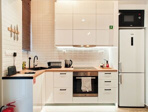 A modern kitchen with white cabinets, a built-in oven, a microwave, and a sink. - Sleek Studio in Voula Center (Voula)