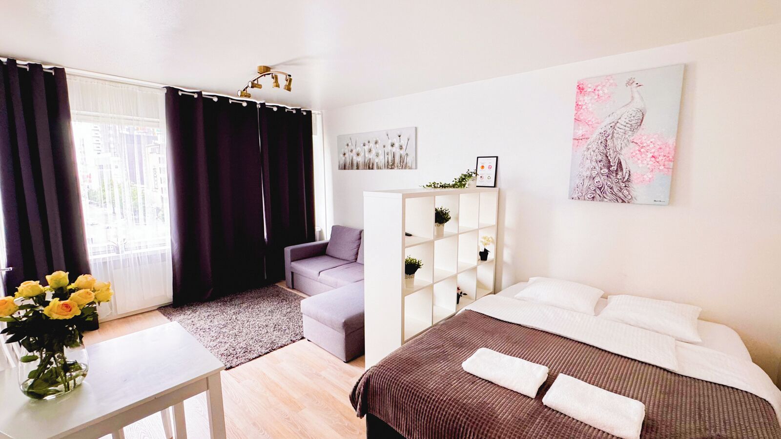 A modern bedroom with a bed, a sofa, a desk, and a window with curtains.