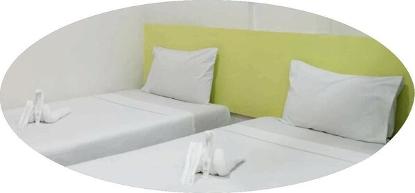 A hotel room with two single beds, each with a white mattress and pillow, and a green headboard. - Sulit Budget Hotel - Dumaguete (Dumaguete)