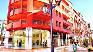 A multi-story building with balconies, a street lamp, and a tiled plaza. - Plaza Downtown Mcdonald's Apartment (Marrakech)