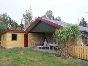 A two-story house with a covered patio, a small shed, and a tall plant. - 5 Star Holiday Home in Vaeggerlose (Vaeggerlose)