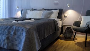Un dormitorio moderno con cama, mesita de noche, silla y pared con diseño abstracto.