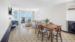 Ein modernes Wohnzimmer mit Essbereich, großen Fenstern und einem Kamin.