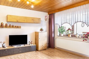 A living room with a TV, wooden cabinet, and potted plants. - Holiday Apartment 'Göpfert' with Wi-Fi (Ebersburg-Weyhers)