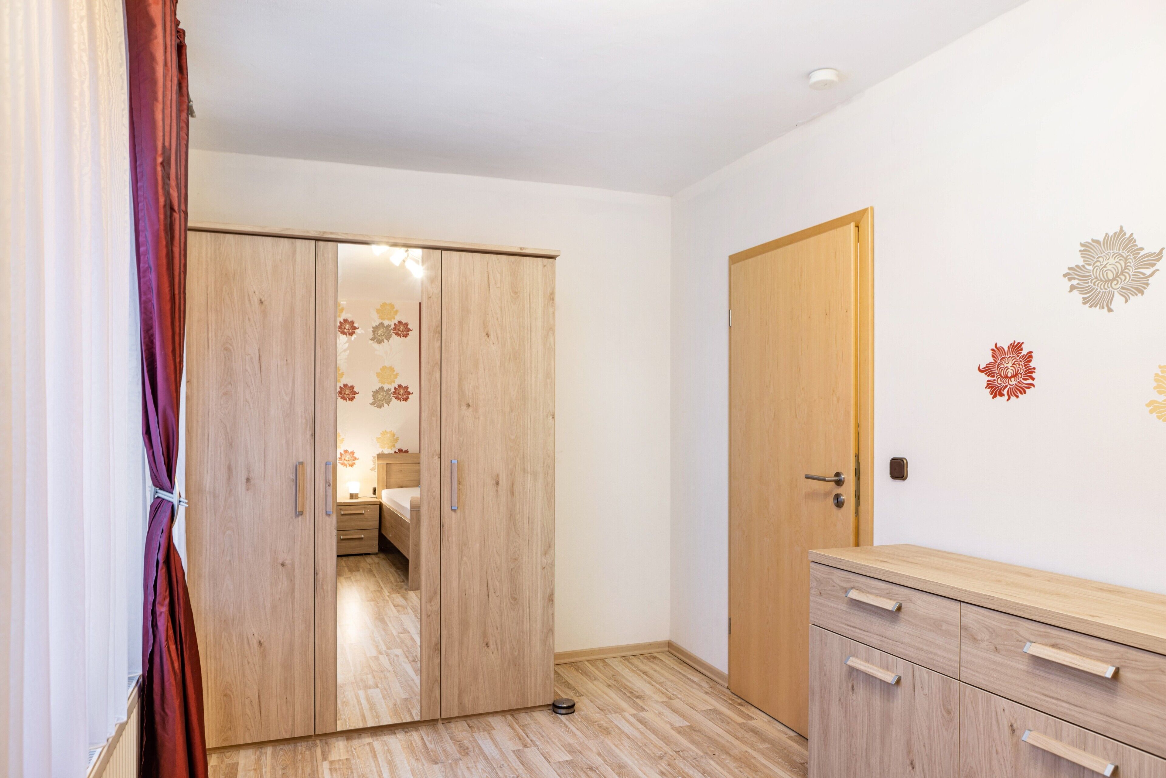 Una habitación con un armario de madera, una cómoda de madera y una puerta con picaporte.