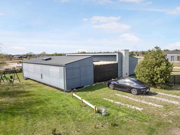 A modern building with a garage and a car parked in front. - 5 Star Holiday Home in Vaeggerlose (Vaeggerlose)