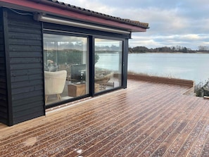 Een modern huis met een terras met uitzicht op een meer.