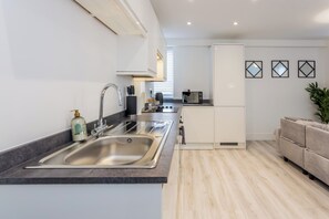 Et moderne køkken med en dobbeltvask, indbygget ovn og et kompakt køleskab.