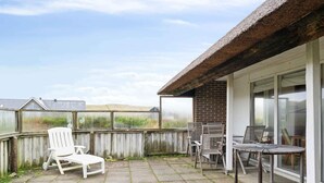 A patio with a thatched roof, a brick wall, and a view of the landscape. - 5 Star Holiday Home in Harboore (Harboore)