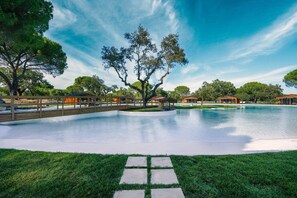 A swimming pool with a wooden deck, surrounded by grass and trees. - Chalet do Lago (Ponte de Sor)
