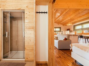 A wooden cabin interior with a glass shower, a sofa, and a bed. - Chalet do Lago (Ponte de Sor)