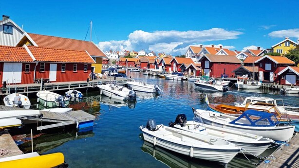 Un port bordé de maisons en bois aux couleurs vives et de bateaux amarrés au quai.