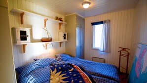 A bedroom with a bed, wooden shelves, a window with curtains, and a map on the wall. - Two charming cottages in Hälleviksstrand | SE09133 (Hälleviksstrand)