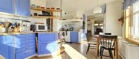 A kitchen with blue cabinets, a microwave, and a dining area with a table and chairs.