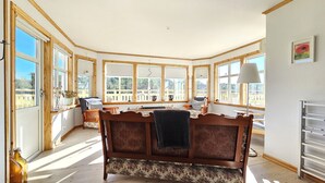 A cozy room with a wooden dining table, chairs, and a large window with a view of greenery. - Family-friendly house close to sea & nature in Klövedal | SE09145 (Klövedal)