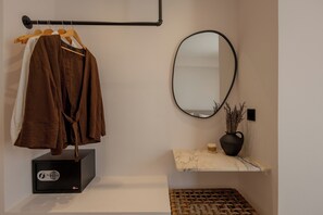A bathroom with a towel rack holding a brown towel, a black safe, a marble shelf with a vase, and a woven mat.