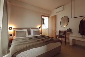 A neatly arranged bedroom with a bed, bedside tables, a chair, a mirror, and a bench.